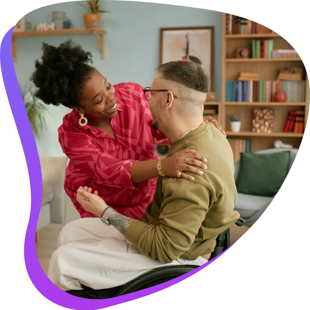 Support worker hugging disabled man in wheelchair