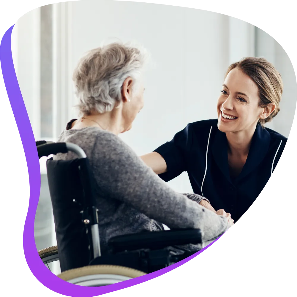 Happy nurse talking with elderly patient in wheelchair